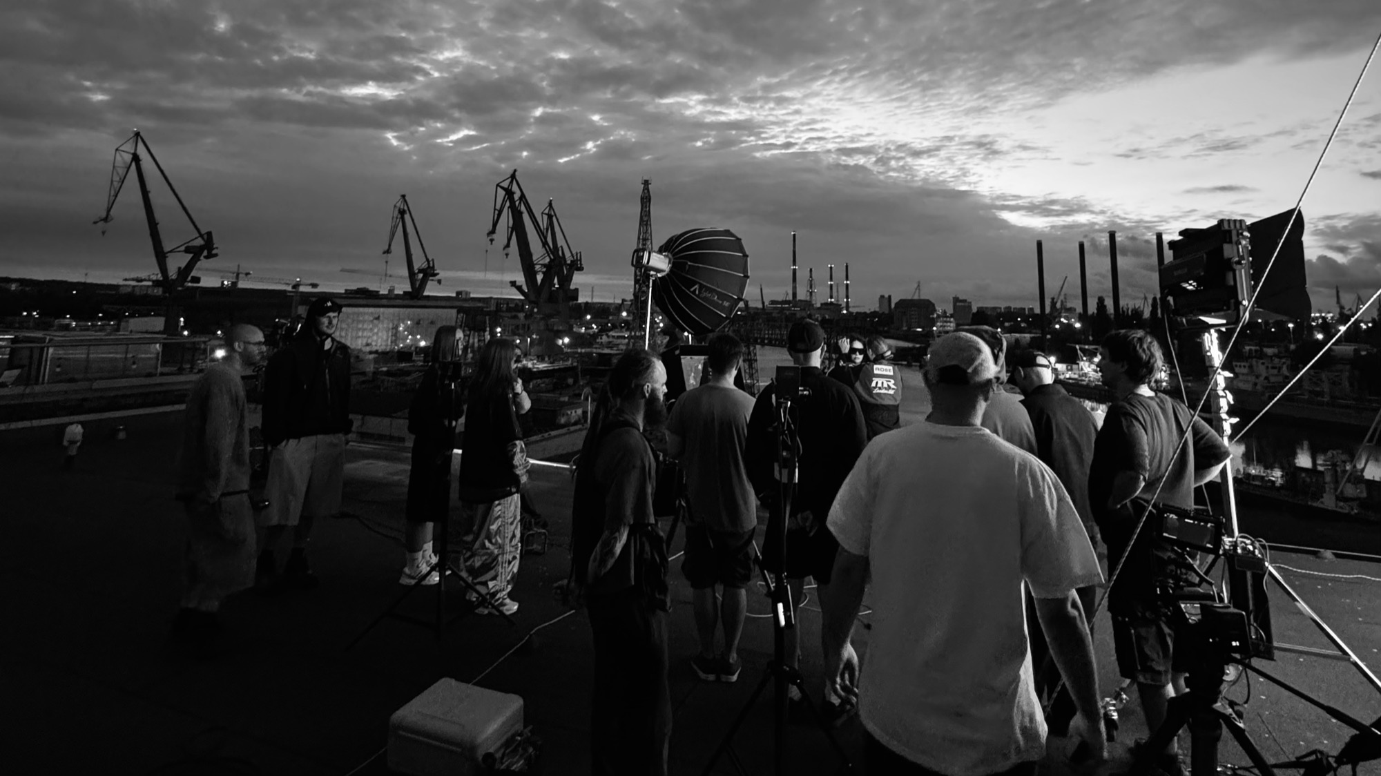 September crew on set at dusk, Gdańsk shipyard cranes behind the camera